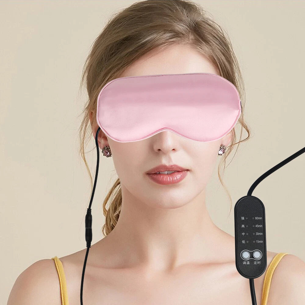 A woman wearing a pink heated sleep mask with a connected black remote control.