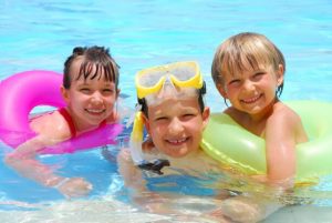 kids at the beach wearing wearing earplugs for swimming