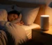White noise machine on bedside table in a softly lit bedroom.
